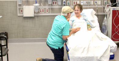Patient at Smith County Memorial Hospital receives care and is comforted by her husband.